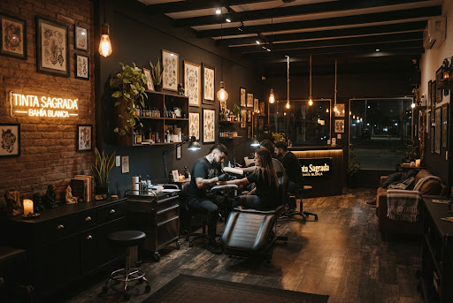 Interior cálido del estudio de tatuajes en Bahía Blanca con ladrillo a la vista y luces neón